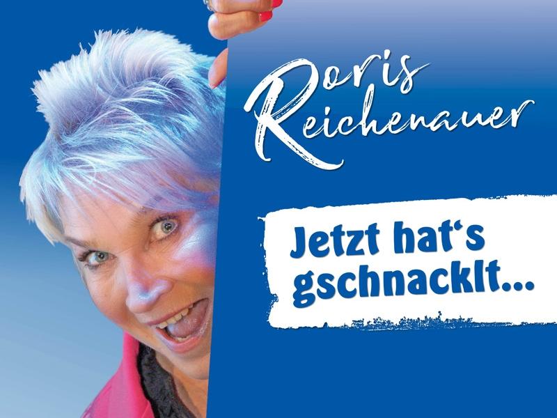 Doris Reichenauer angeschnitten vor blauem Hintergrund, ihre Hand oben, als ob sie hinter einer wand steht, darauf der Schriftzug : Doris Reichenauer Jetzt hats geschnacklt...