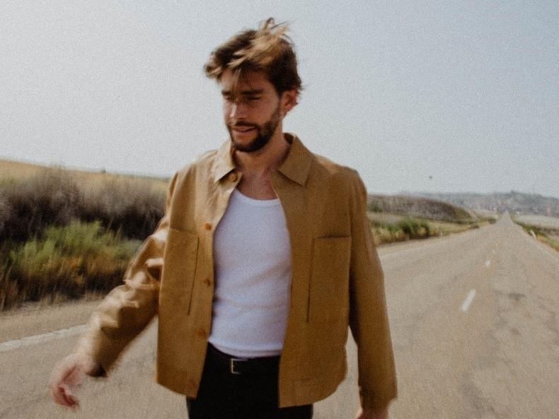 Alvaro Soler läuft mit weißem T-Shirt und offener brauner Jacke auf einer Straße, das Bild ist durch die Bewegung leicht unscharf